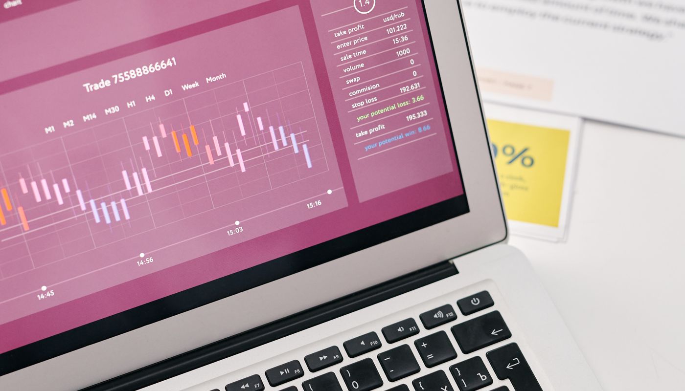 Laptop displaying graphs beside printed reports
