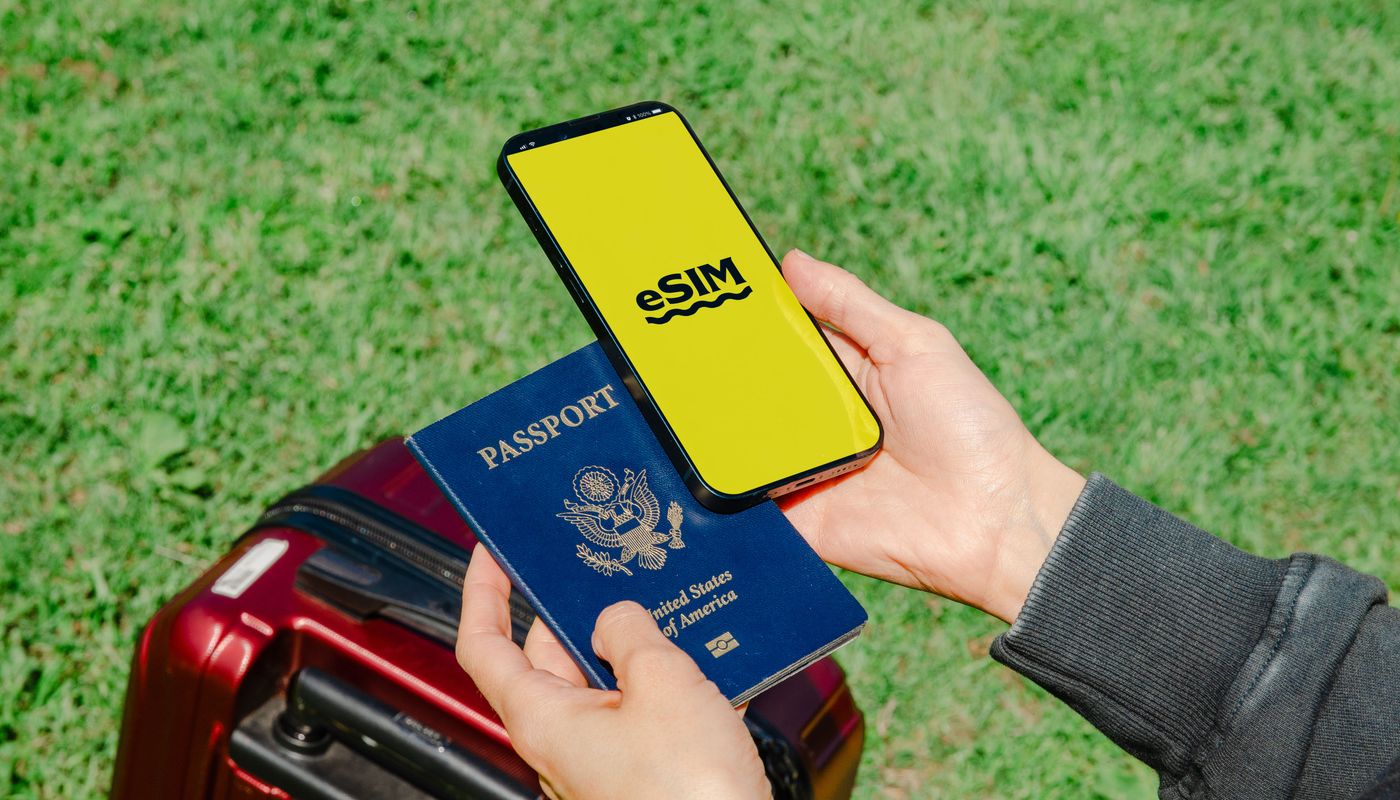 Hands holding a passport and smartphone